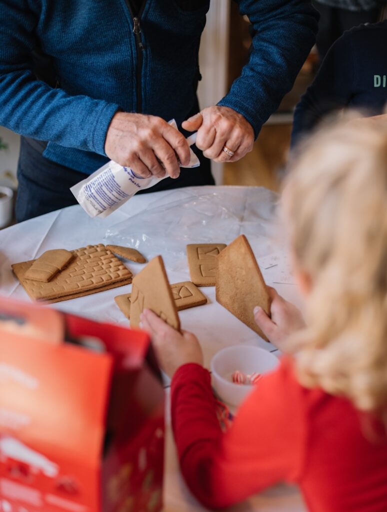 child holding crackers and another person holding whipped cream while standing