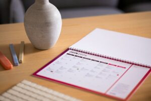 A calendar and vase sit on a wooden desk.